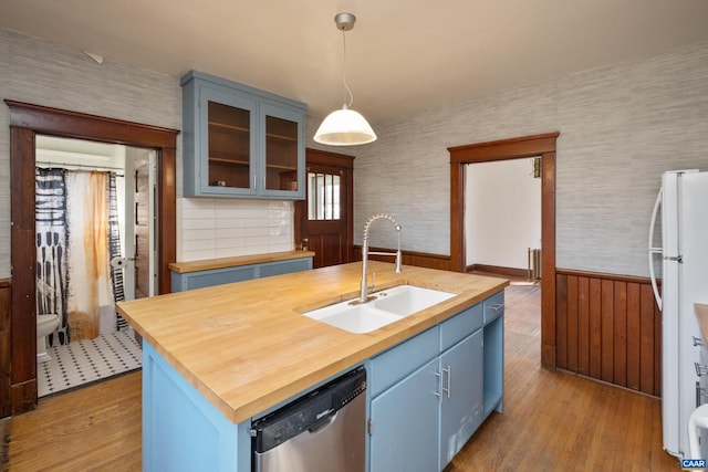 kitchen featuring blue cabinets, hanging light fixtures, stainless steel dishwasher, and light wood-type flooring