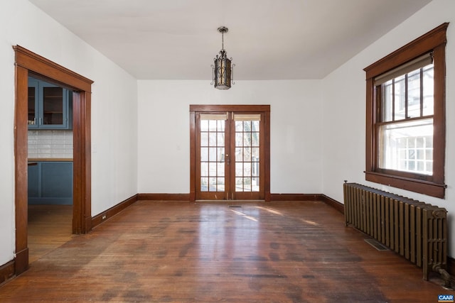 spare room featuring dark hardwood / wood-style floors, a healthy amount of sunlight, and radiator heating unit