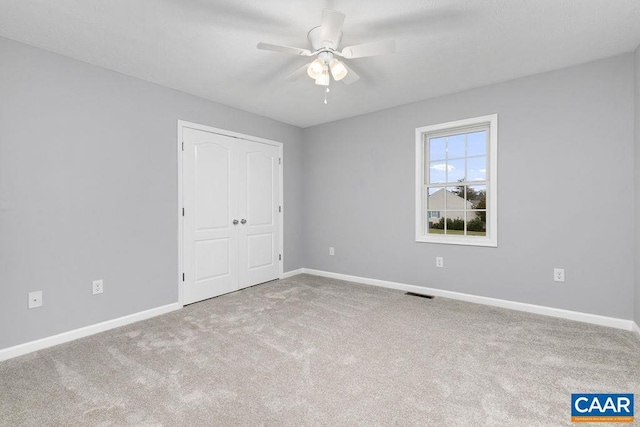 unfurnished bedroom with ceiling fan, a closet, and carpet