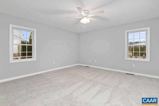 carpeted empty room with ceiling fan and plenty of natural light