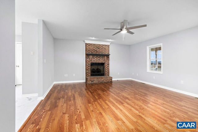 unfurnished living room featuring hardwood / wood-style flooring, ceiling fan, and a brick fireplace