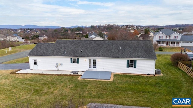 back of property with a lawn, a mountain view, central AC unit, and a patio