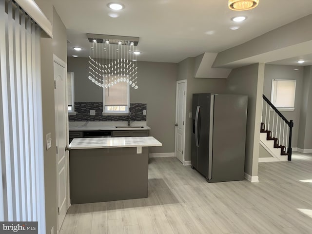 kitchen featuring sink, a chandelier, stainless steel refrigerator with ice dispenser, and light wood-type flooring