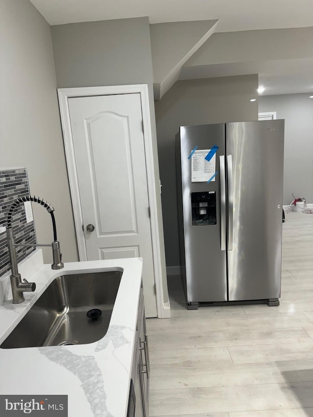 kitchen with stainless steel fridge, light hardwood / wood-style floors, and sink