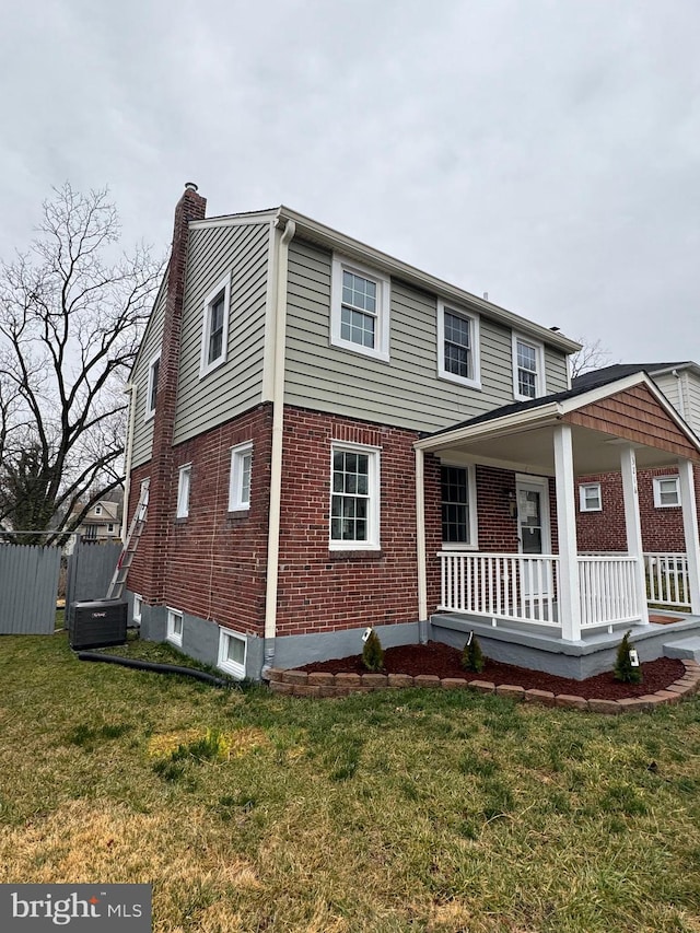 view of front of property featuring central AC unit, covered porch, and a front lawn