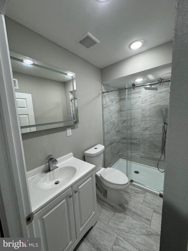 bathroom featuring vanity, a shower with shower door, and toilet