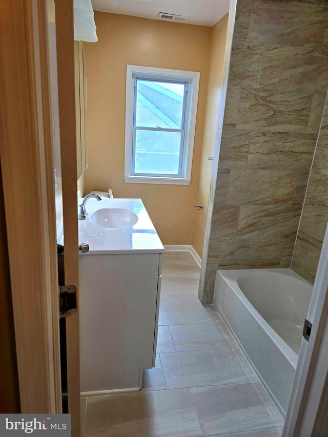 bathroom with a bath, vanity, and tile patterned floors