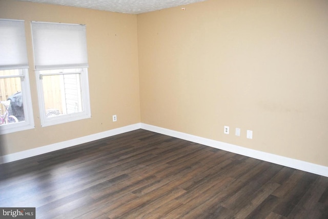 empty room featuring a textured ceiling and dark hardwood / wood-style floors