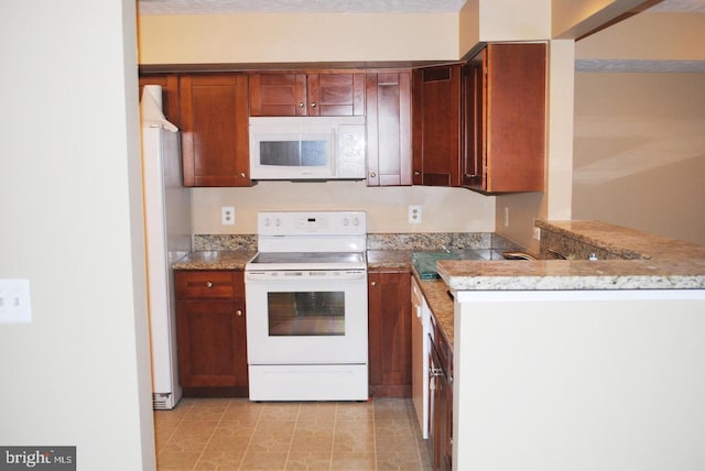 kitchen with kitchen peninsula, stone countertops, and white appliances