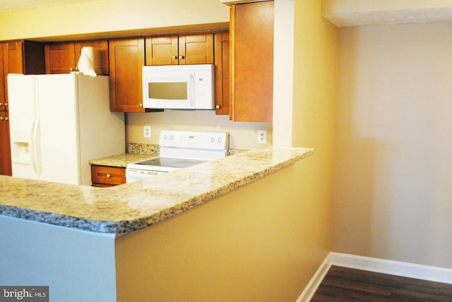 kitchen featuring kitchen peninsula, light stone counters, dark hardwood / wood-style flooring, and white appliances