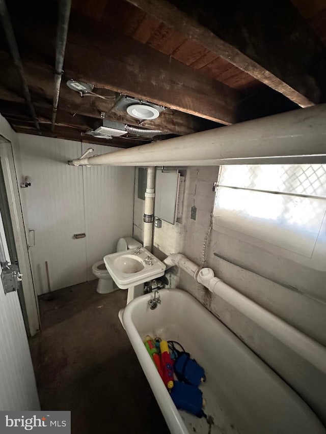 bathroom with a bathing tub, sink, concrete flooring, and toilet