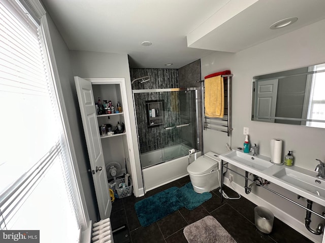 full bathroom with sink, shower / bath combination with glass door, tile patterned flooring, radiator heating unit, and toilet