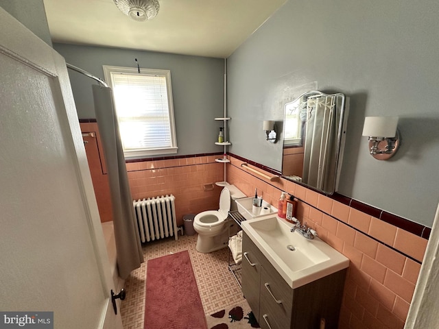 bathroom with vanity, toilet, radiator heating unit, and tile walls