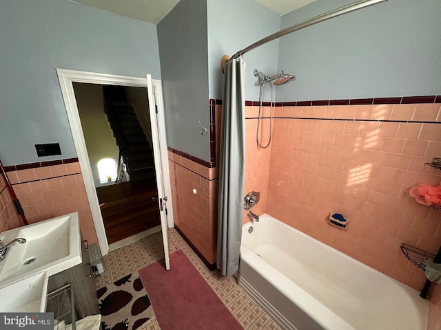 bathroom featuring tile patterned flooring, shower / tub combo, tile walls, and sink