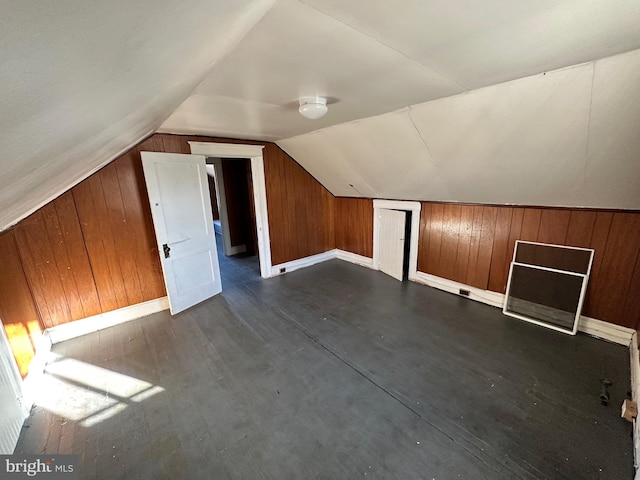 bonus room with lofted ceiling, dark hardwood / wood-style floors, and wooden walls