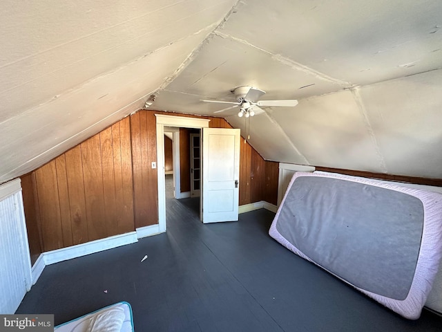 unfurnished bedroom featuring ceiling fan, wood walls, and lofted ceiling