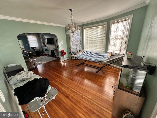 dining space with hardwood / wood-style floors, ornamental molding, and an inviting chandelier