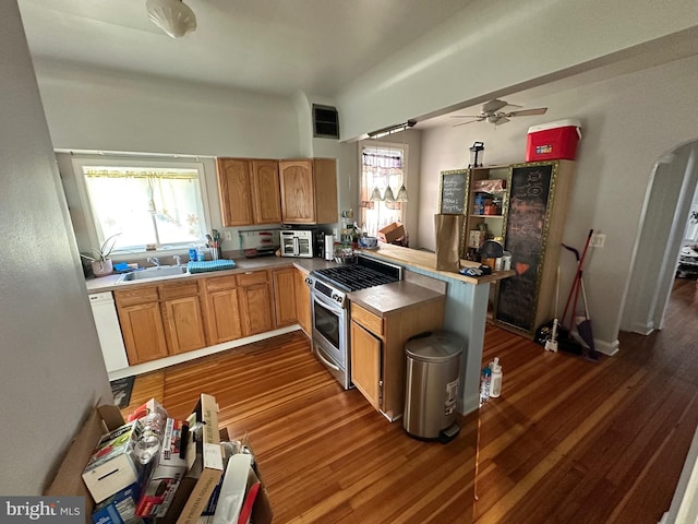 kitchen featuring kitchen peninsula, sink, dark wood-type flooring, and stainless steel range with gas stovetop