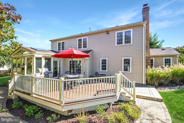 back of property with solar panels, a deck, and a sunroom