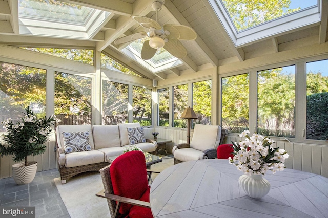 sunroom featuring ceiling fan, vaulted ceiling with skylight, and a healthy amount of sunlight