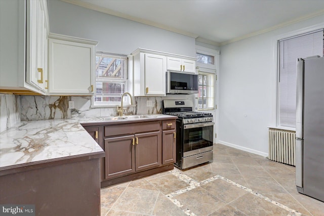 kitchen with light stone counters, stainless steel appliances, crown molding, sink, and white cabinetry