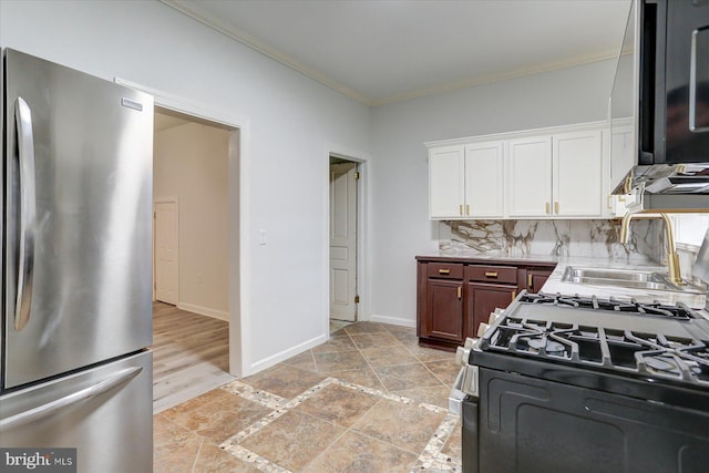 kitchen with decorative backsplash, stainless steel fridge, ornamental molding, sink, and white gas stove