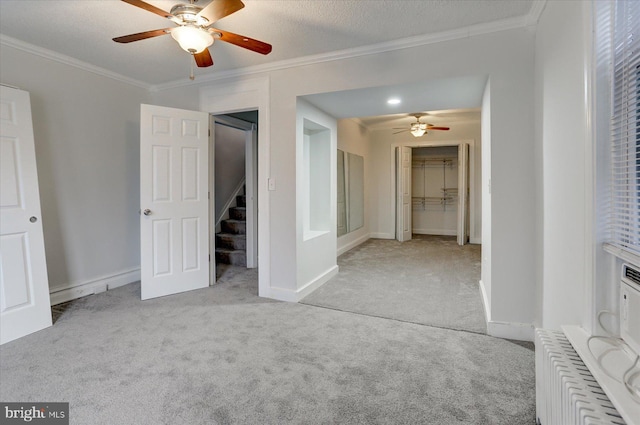 interior space with crown molding, radiator heating unit, ceiling fan, and a textured ceiling