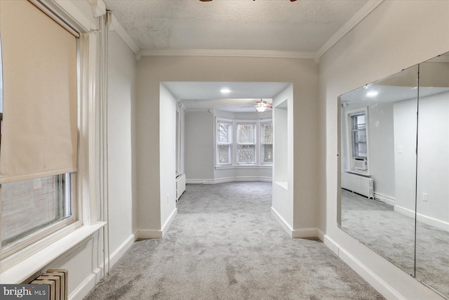 hall featuring a textured ceiling, light colored carpet, radiator heating unit, and crown molding