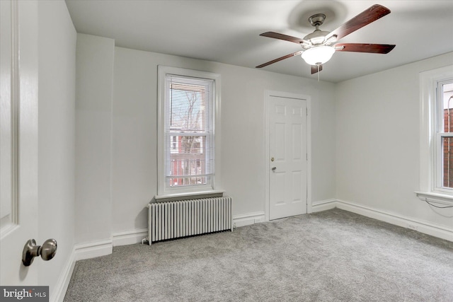 carpeted empty room featuring ceiling fan and radiator