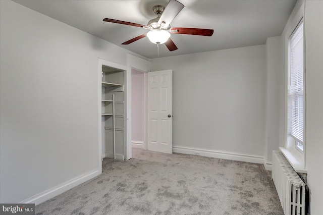 unfurnished bedroom featuring radiator, ceiling fan, a closet, and light carpet