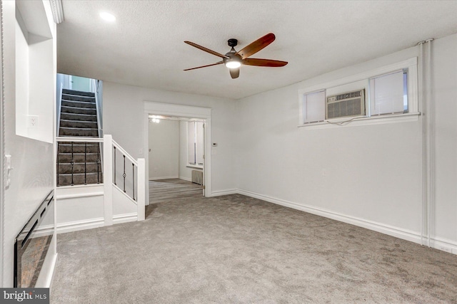 carpeted empty room with baseboard heating, ceiling fan, cooling unit, and a textured ceiling