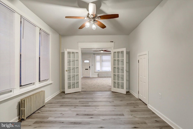 unfurnished room featuring light hardwood / wood-style floors, radiator heating unit, and french doors