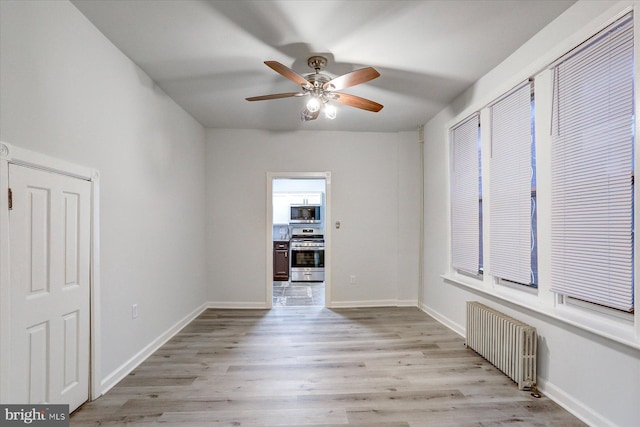 unfurnished room featuring light hardwood / wood-style flooring, radiator, and ceiling fan