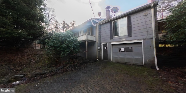 view of side of home with a garage and a balcony