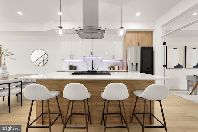 kitchen featuring white cabinetry, stainless steel appliances, hanging light fixtures, light hardwood / wood-style floors, and island range hood