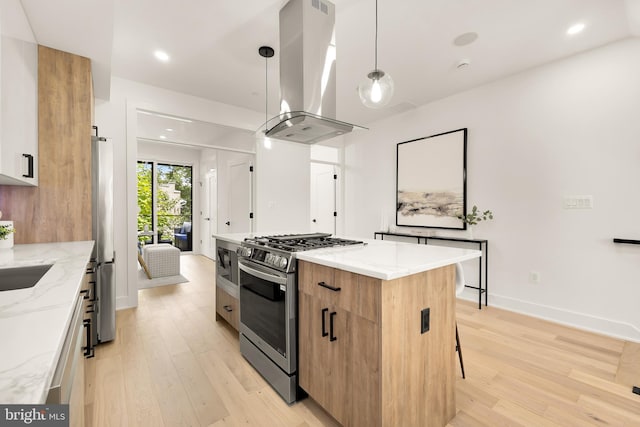 kitchen with pendant lighting, light wood-type flooring, light stone countertops, appliances with stainless steel finishes, and island exhaust hood