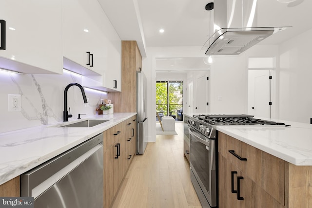 kitchen with pendant lighting, white cabinets, light hardwood / wood-style flooring, light stone countertops, and stainless steel appliances