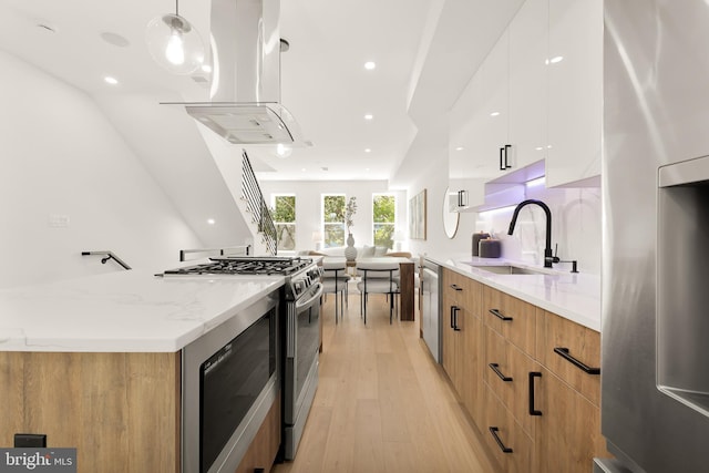 kitchen featuring sink, ventilation hood, decorative light fixtures, white cabinets, and appliances with stainless steel finishes