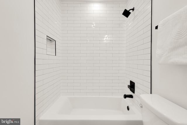 bathroom with tiled shower / bath combo and toilet