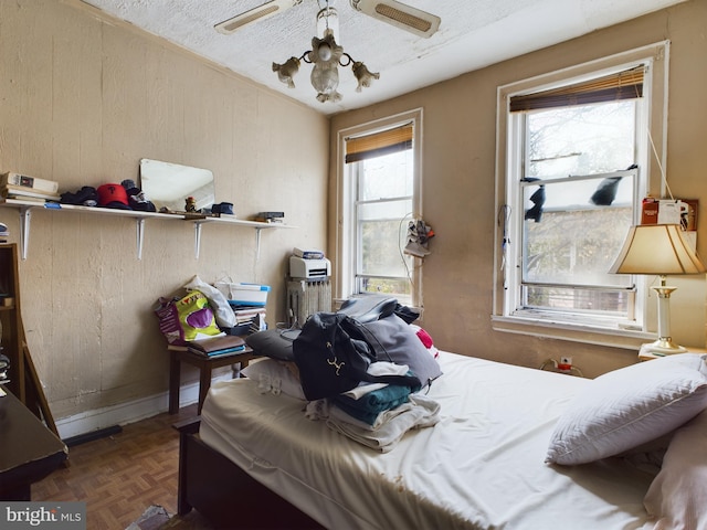 bedroom featuring ceiling fan, dark parquet flooring, a textured ceiling, and multiple windows