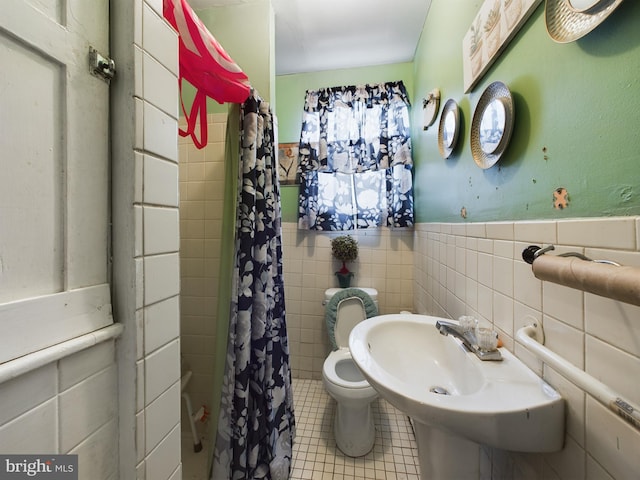 bathroom with toilet, a shower with shower curtain, tile patterned floors, and tile walls