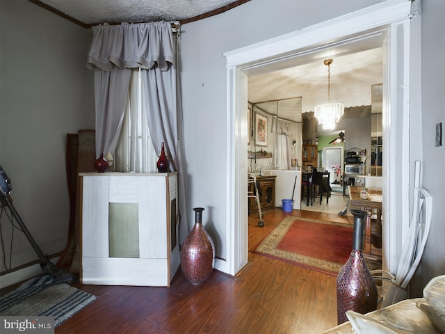 interior space with hardwood / wood-style flooring, a notable chandelier, ornamental molding, and a textured ceiling