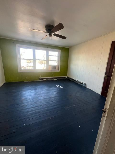 spare room featuring ceiling fan, a healthy amount of sunlight, and dark wood-type flooring