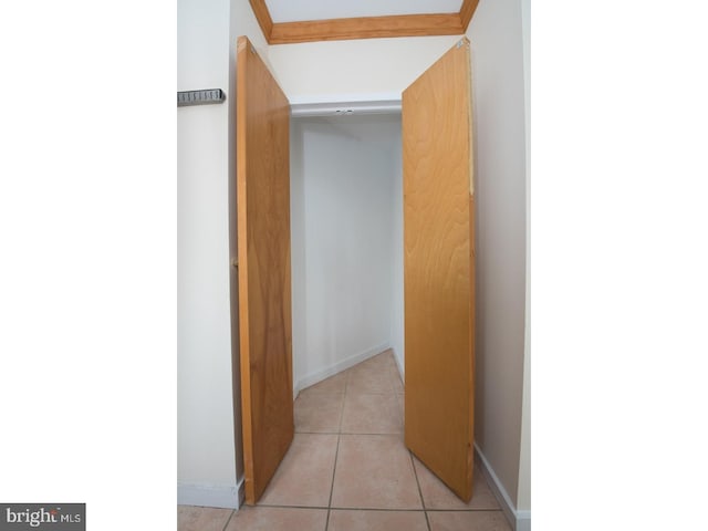 corridor with light tile patterned floors and ornamental molding