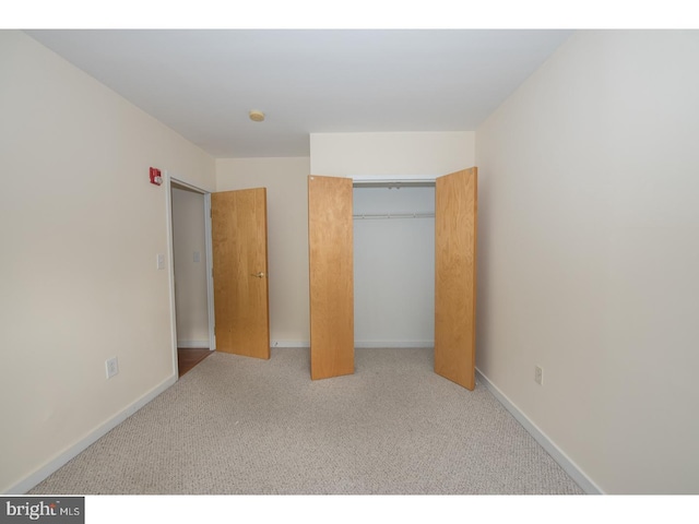 unfurnished bedroom featuring light colored carpet and a closet