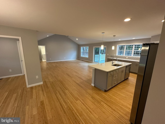 kitchen featuring gray cabinetry, stainless steel appliances, lofted ceiling, a kitchen island with sink, and light wood-type flooring