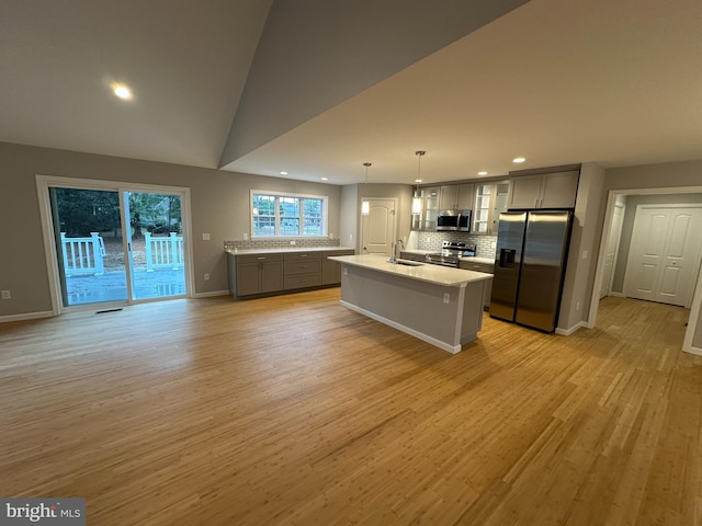 kitchen with gray cabinets, a center island with sink, light hardwood / wood-style floors, and appliances with stainless steel finishes