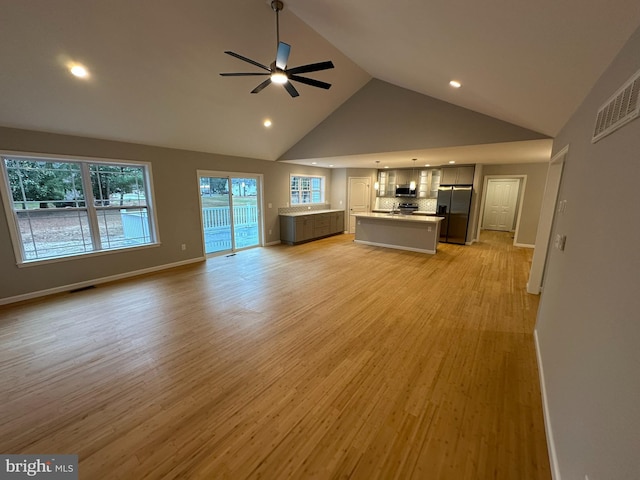 unfurnished living room featuring light wood-type flooring, high vaulted ceiling, and ceiling fan