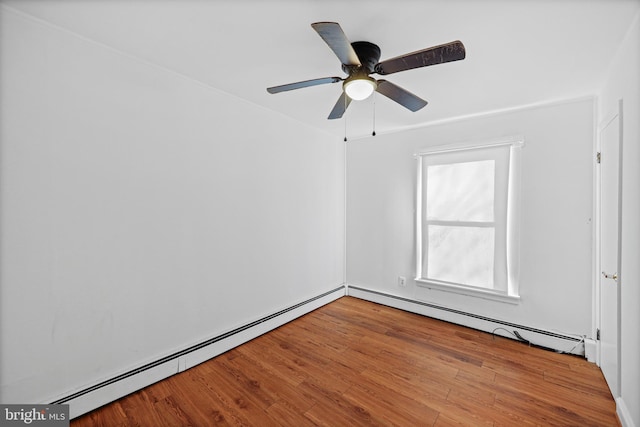 spare room with wood-type flooring, ceiling fan, and a baseboard heating unit