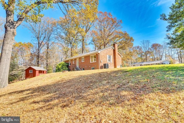 view of side of property with a shed, central AC unit, and a lawn